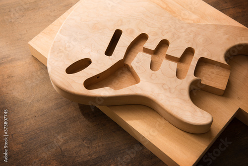 Electric guitar making. Guitar work shop. Unfinished solidbody electric guitar body on work bench. Shallow depth of field. photo