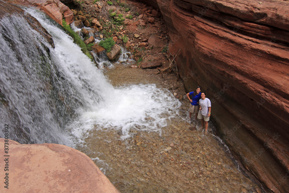 Grand Canyon National Park, Arizona - May 18, 2010 - Two young women enjoy small waterfall in Deer Creek on summer backpacking trip.