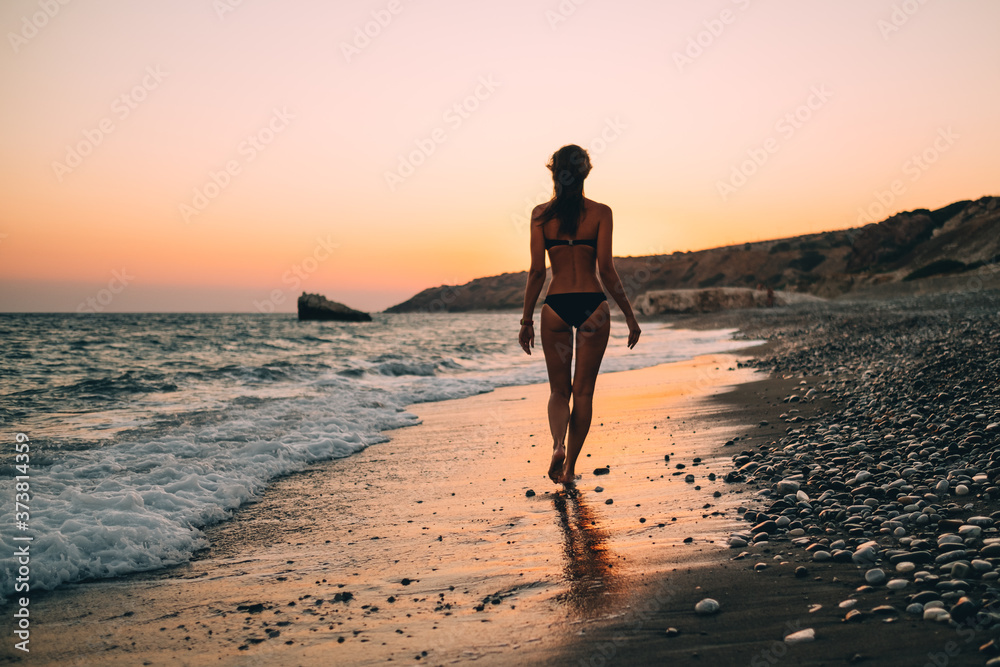Young sexy caucasian woman walking along ocean beach