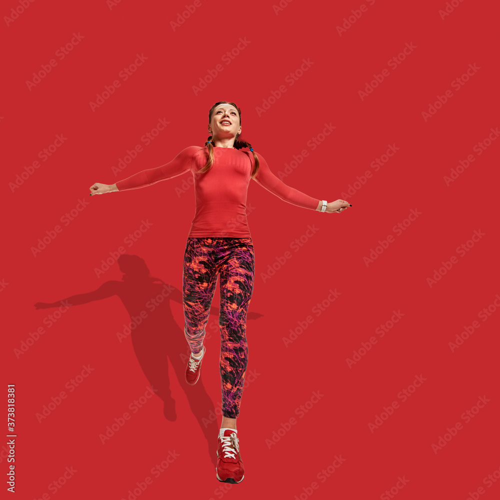 Obraz premium Young slim healthy woman running marathon red background with shadow