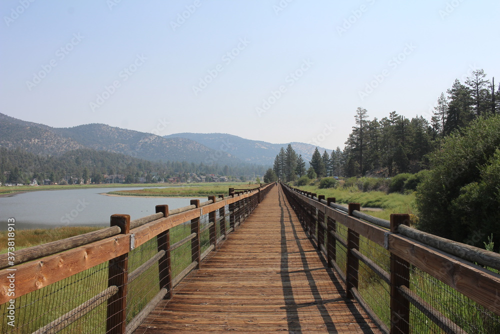 Wooden bridge path along the river on a clear blue sky day in the mountains