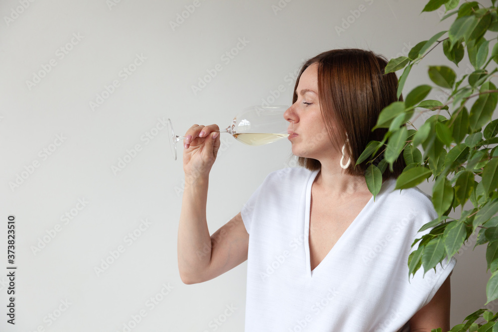 Caucasian brunette girl sommelier drinking white wine from glass Caucasian brunette girl sommelier drinking white wine from glass