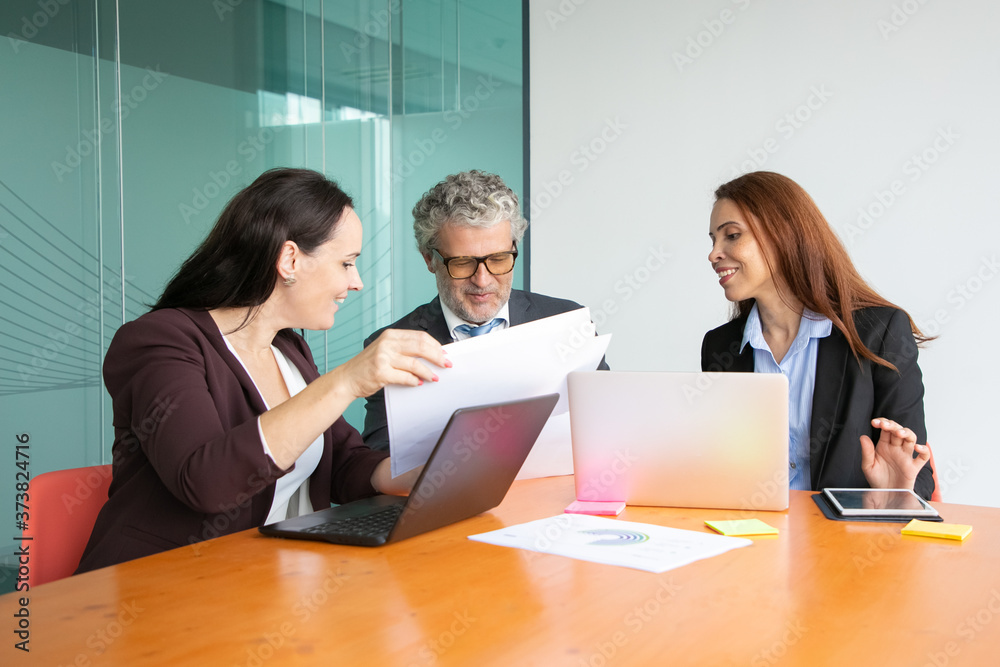 Managers presenting paper reports to boss. Grey haired man in suit and two business women reviewing papers together. Business and paperwork concept Managers presenting paper reports to boss. Grey haired man in suit and two business women reviewing papers together. Business and paperwork concept
