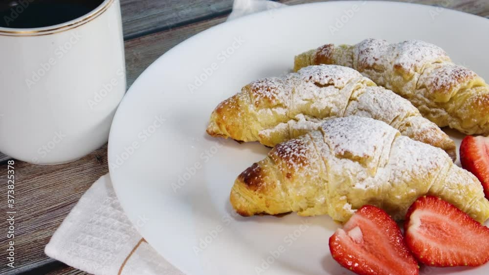 Pouring red syrup on sweet croissants on white plate. Delicious croissants for breakfast or snack 