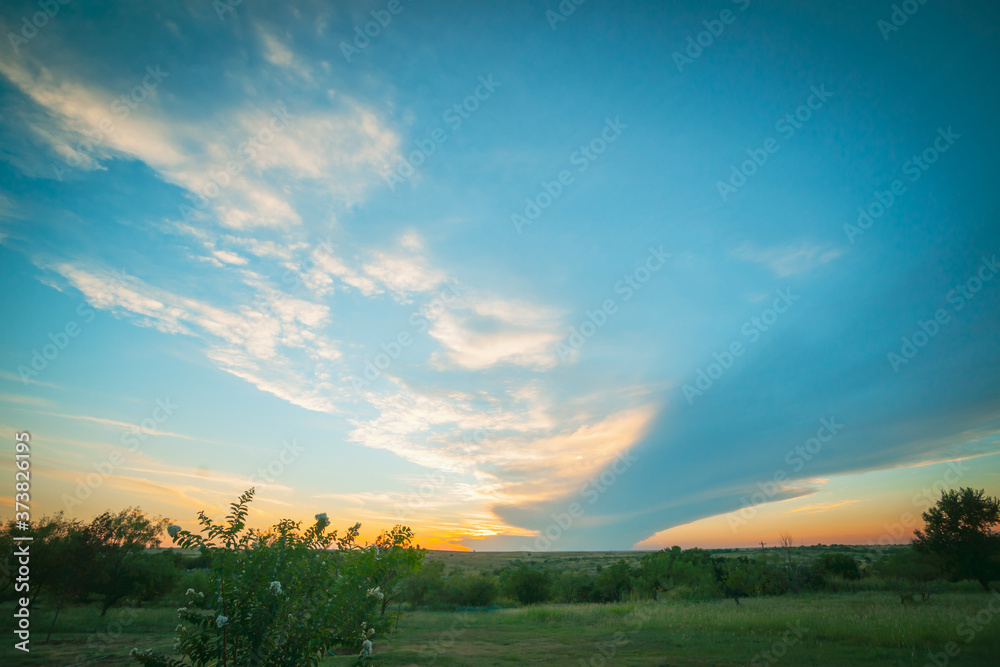 Shelf cloud spans over Texan landscape at sunset.