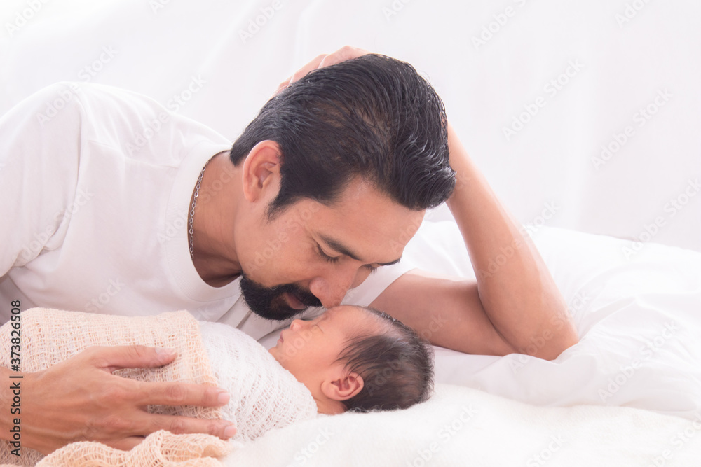 Handsome happy Asian men with beard dad kissing healthy toddler newborn baby in bed at home, Healthcare medical lifestyle father day/ parenthood concept, infant sleep safe and protection bonding Handsome happy Asian men with beard dad kissing healthy toddler newborn baby in bed at home, Healthcare medical lifestyle father day/ parenthood concept, infant sleep safe and protection bonding