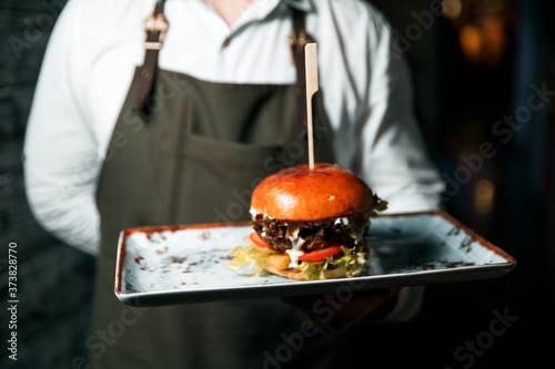 Fresh tasty hamburger, ready to serve lies in a plate.