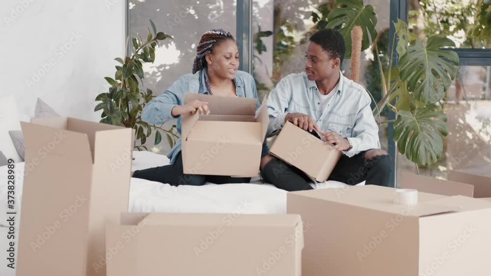 A young wife is packing boxes with her husband. The couple are moving. This is a consept of people's relocation A young wife is packing boxes with her husband. The couple are moving. This is a consept of people's relocation