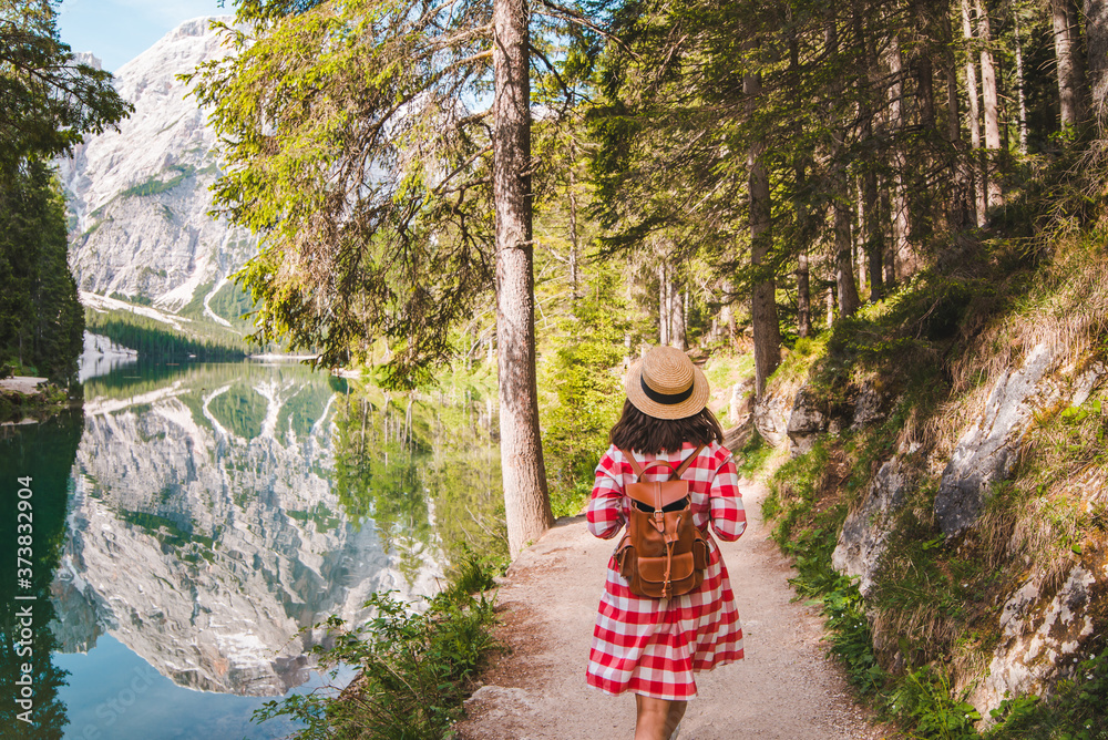 Naklejka premium woman in red checkered dress walking around mountain lake