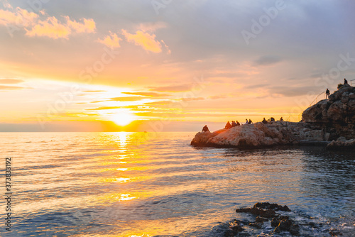 people resting at the beach of the sea enjoying view of sunset