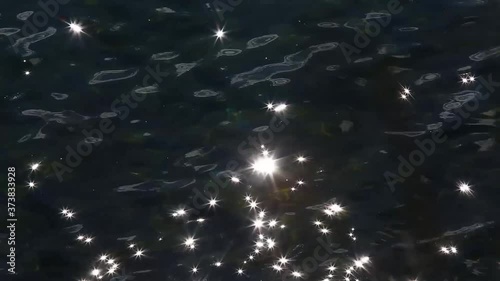 Glare of sun in Baikal water waves look like stars turning into blur