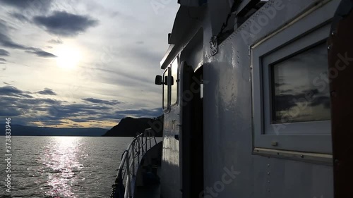 Small Ship Slowly Moving Forward Towards the Quiet Shores of the Lake - Lake Baikal, Russia at cloudy weather