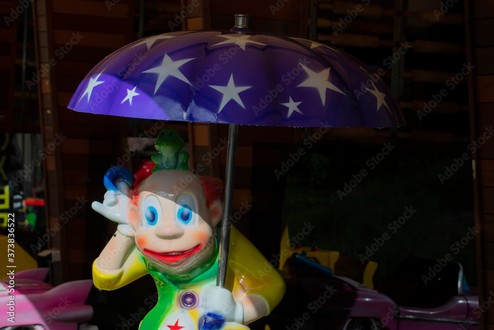 Fototapeta premium Toy bright clown under a blue umbrella.
