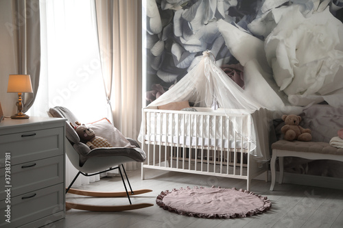 Baby room interior with stylish crib and floral wallpaper © New Africa