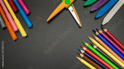 Education concept. School stationery with colorful pencils, chalk, brushes on black chalkboard in classroom. Banner Concept Back To School.