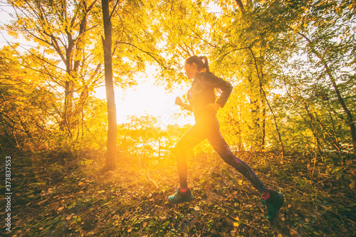 Sport running girl athlete jogging in autum foliage forest. Fall outdoor activity.