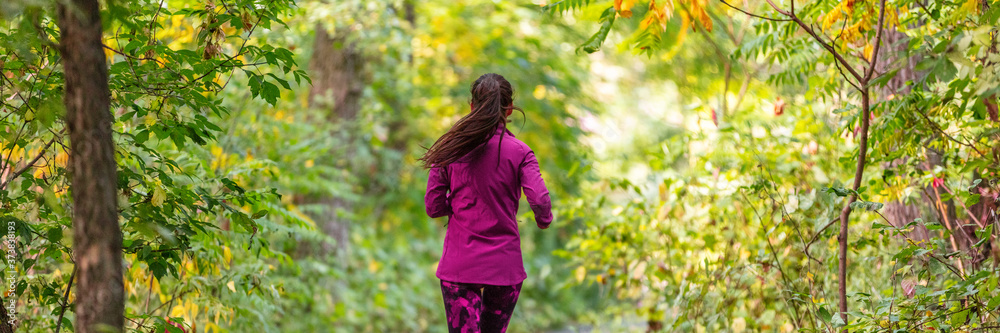Autumn trail run outdoor sports woman running in forest banner. Panoramic crop of runner athlete training cardio outside in nature park. Autumn trail run outdoor sports woman running in forest banner. Panoramic crop of runner athlete training cardio outside in nature park.