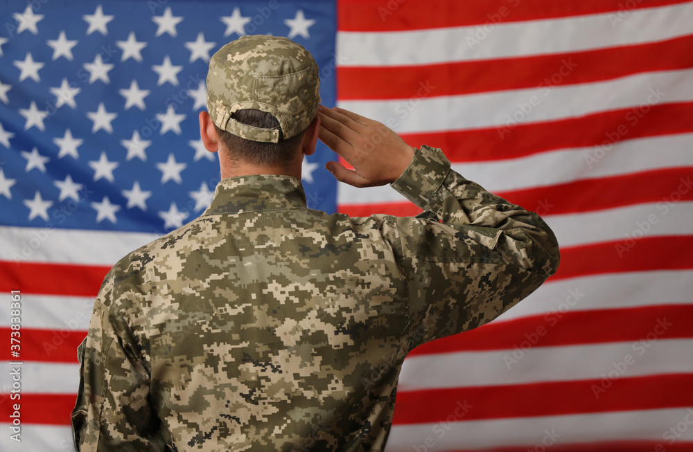 Male soldier in uniform against USA flag, back view Male soldier in uniform against USA flag, back view