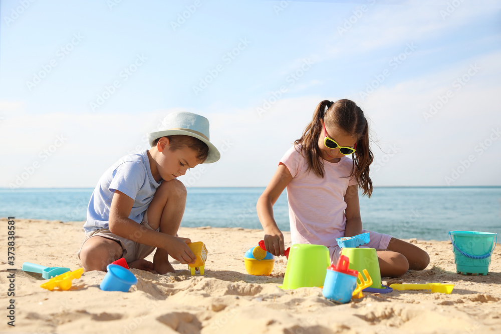 Cute little children playing with plastic toys on sandy beach Cute little children playing with plastic toys on sandy beach