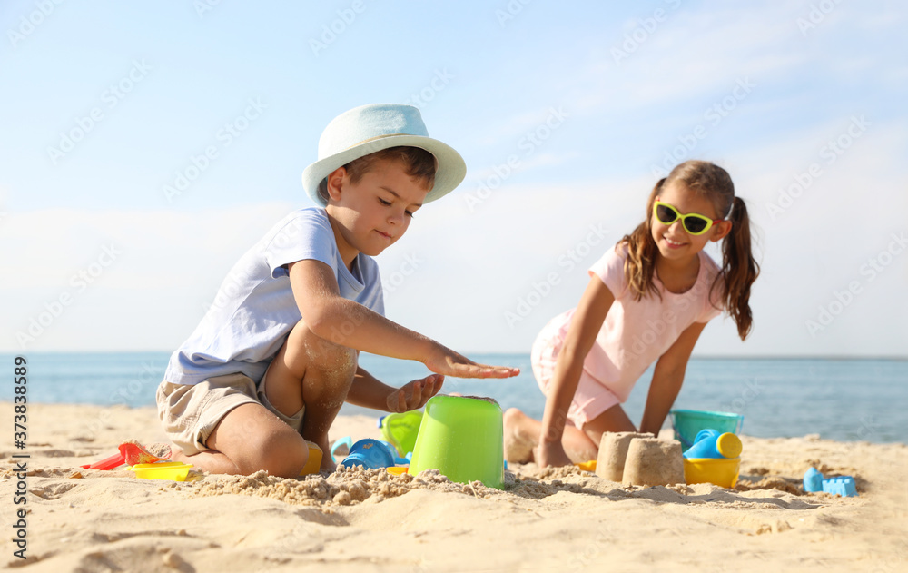 Cute little children playing with plastic toys on sandy beach Cute little children playing with plastic toys on sandy beach
