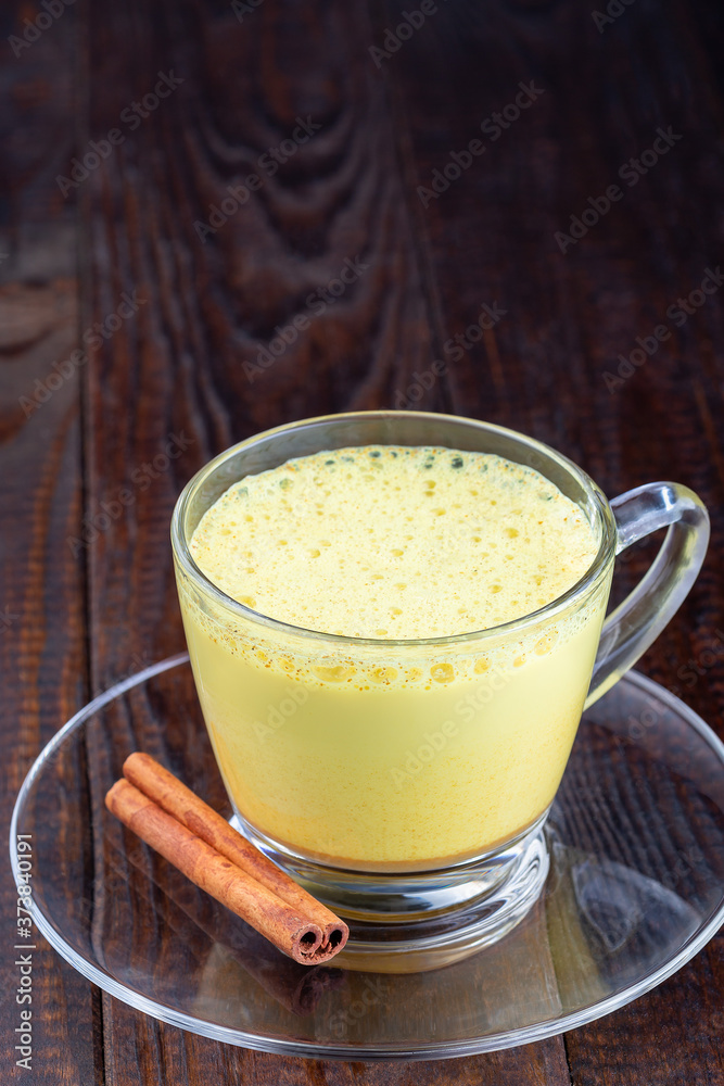 Moon milk with turmeric in  glass cup, vertical, copy space