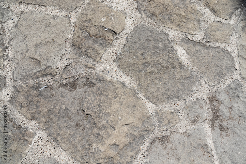 Stone pavement. Texture of stone paved ground. Large jagged stone blocks on a pedestrian sidewalk or road. Ancient masonry. Great for background and design. Stone pavement. Texture of stone paved ground. Large jagged stone blocks on a pedestrian sidewalk or road. Ancient masonry. Great for background and design.