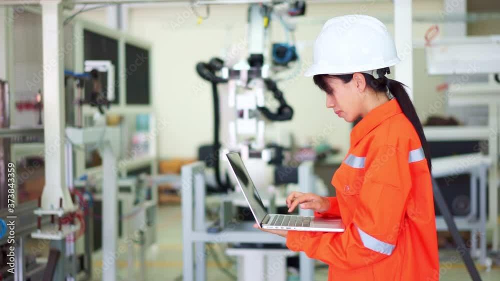 Smart factory concept: A female engineer is setting industrial robot by computer laptop. Smart factory concept: A female engineer is setting industrial robot by computer laptop.