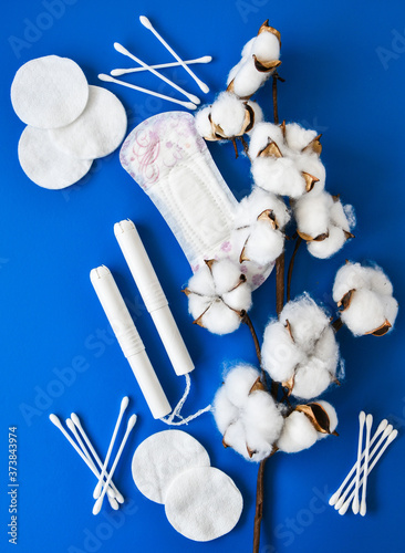 All made of cotton. Hygiene accessories - sanitary napkins, cotton pads, cotton swabs, tampons on blue background. Concept of critical days, menstruation. Zero waste eco-friendly photo