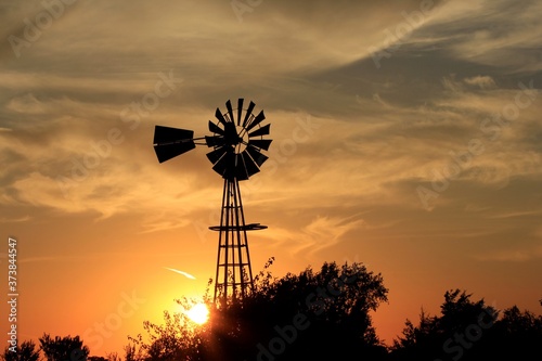 Kansas Sunset with a colorful sky and clouds with a Windmill silhouette north of Hutchinson Kansas USA.