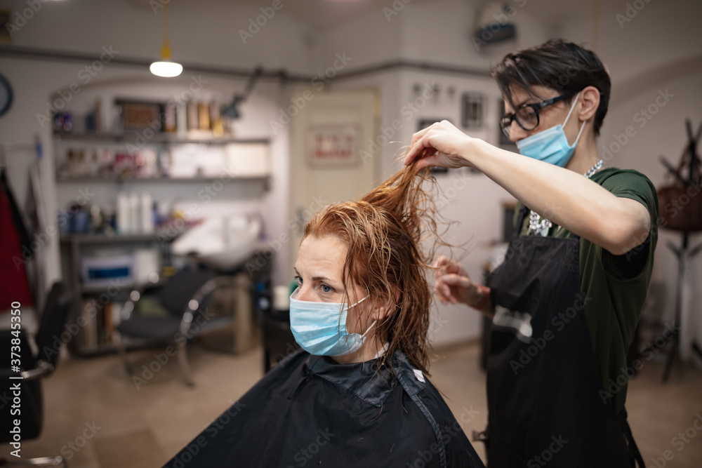 Hairdresser and customer in a salon with medical masks during virus pandemic. Working with safety mask. Hairdresser and customer in a salon with medical masks during virus pandemic. Working with safety mask.