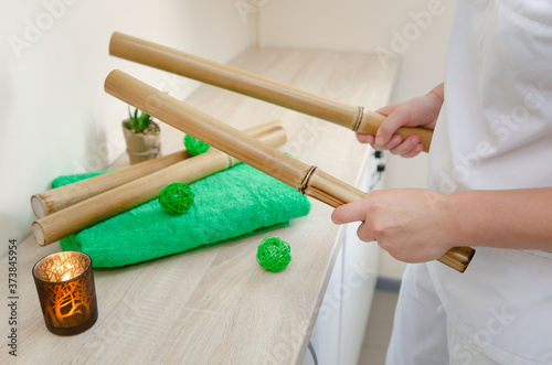 
Close-up of the hands of the masseur holding bamboo sticks. Spa, wellness concept on bamboo background