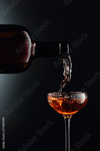 Strong golden alcoholic drink from the antique bottle being poured into a  glass.