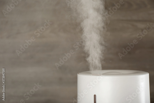 Modern air humidifier on wooden background, closeup. Space for text