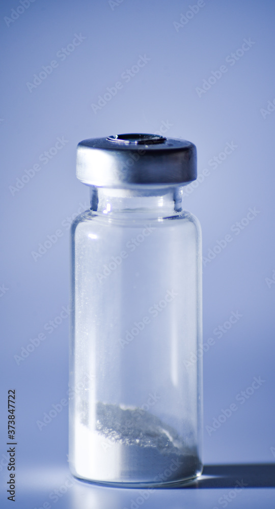 glass medical vial with white powder on white background. Close up. Isolated glass medical vial with white powder on white background. Close up. Isolated