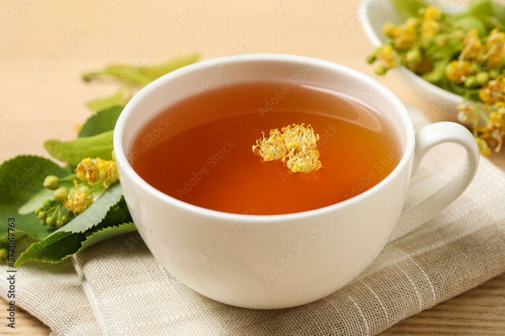 Cup of tea with linden blossom on table, closeup