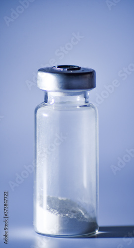glass medical vial with white powder on white background. Close up. Isolated