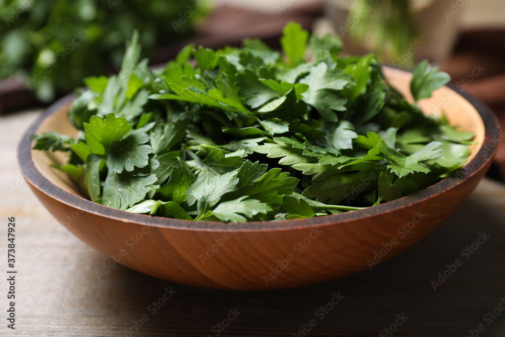 Fresh green parsley in bowl on wooden table Fresh green parsley in bowl on wooden table