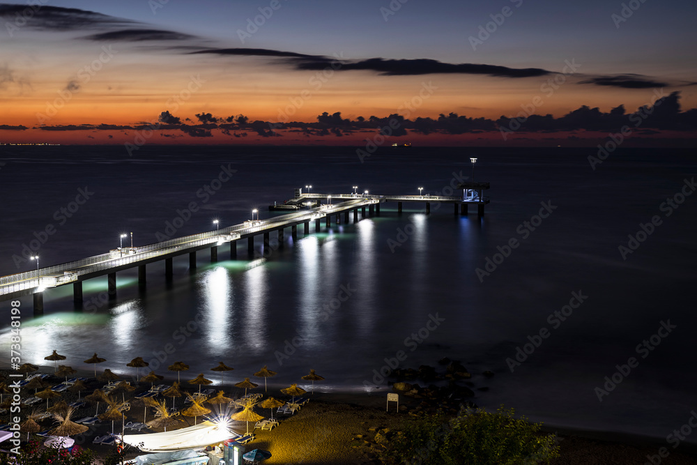 Night view of Dramatic colorful sunrise with  clouds over the sea bridge in Burgas. Symbol of the sity.	