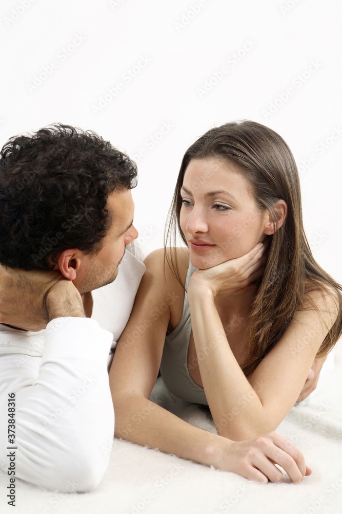 Man and woman lying forward, looking at each other Man and woman lying forward, looking at each other