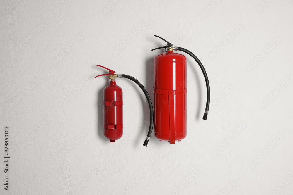 Different fire extinguishers hanging on white wall Different fire extinguishers hanging on white wall