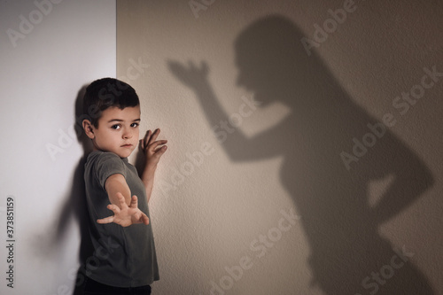 Child abuse. Mother yelling at her son. Shadow of woman on wall