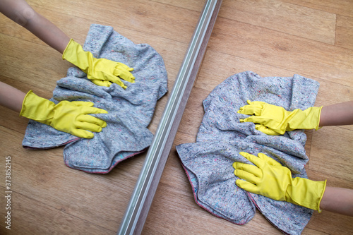 Girl in rubber gloves washes the floor at home near the mirror with a rag. Concept of housework and housekeeping