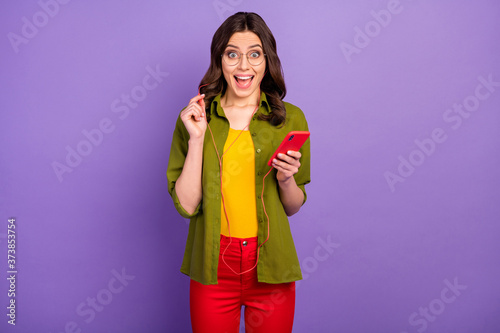 Portrait of astonished positive girl use smartphone listen incredible radio melody headset impressed scream wow omg wear style stylish trendy headset isolated violet color background