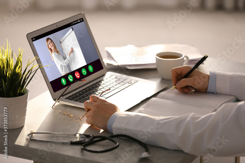 Doctor having online video consultation with business trainer at table  closeup