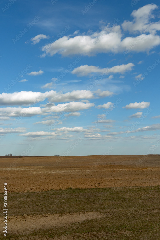 Beautiful cloudy sky over farmland. Spring landscape.