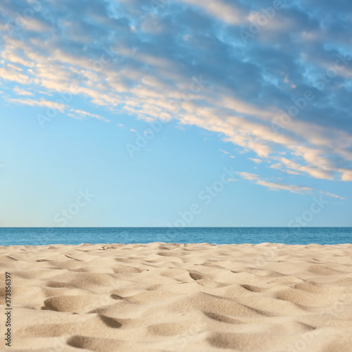 Sandy beach near sea under blue sky with clouds