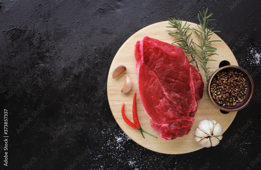 Raw beef steak with spices on plate, stone or concrete background. Top view with copy space.