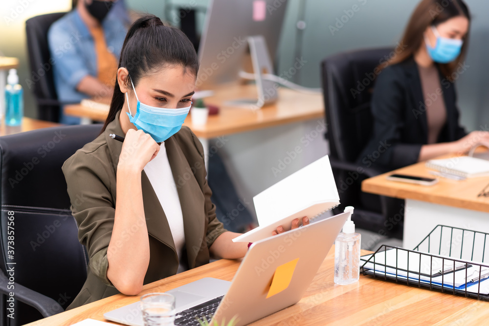 Asian businesswoman wearing mask calling with smartphone at night in office show new normal office lifestyle Asian businesswoman wearing mask calling with smartphone at night in office show new normal office lifestyle