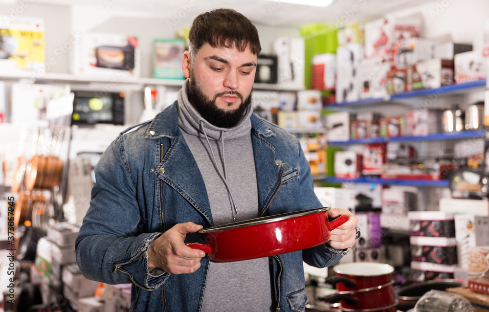 Satisfied man buys new pan in the hardware store. High quality photo
