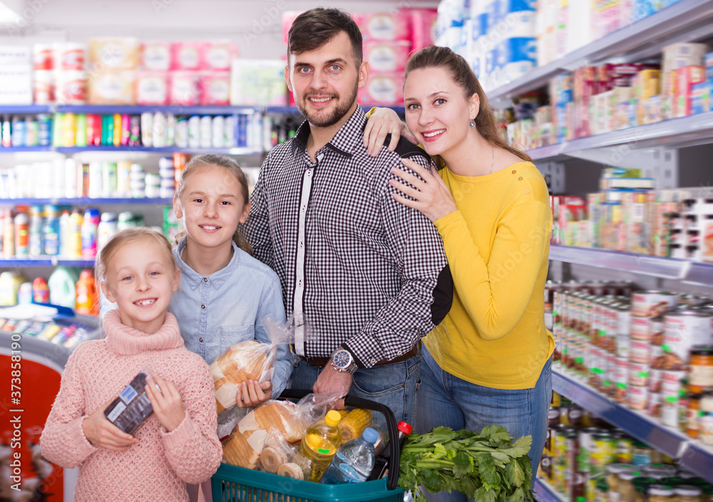Adult friendly family of four with full shopping basket in supermarket